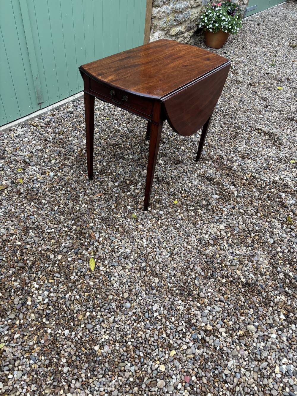 A small Georgian mahogany Pembroke table featuring two rounded drop leaves, a single frieze drawer, and four square tapered legs. View IV
