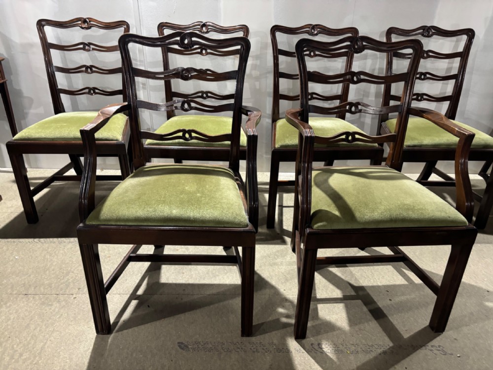 A set of six dark mahogany ladderback dining chairs, including two carvers and four side chairs, featuring serpentine carved splats and green velvet seats.