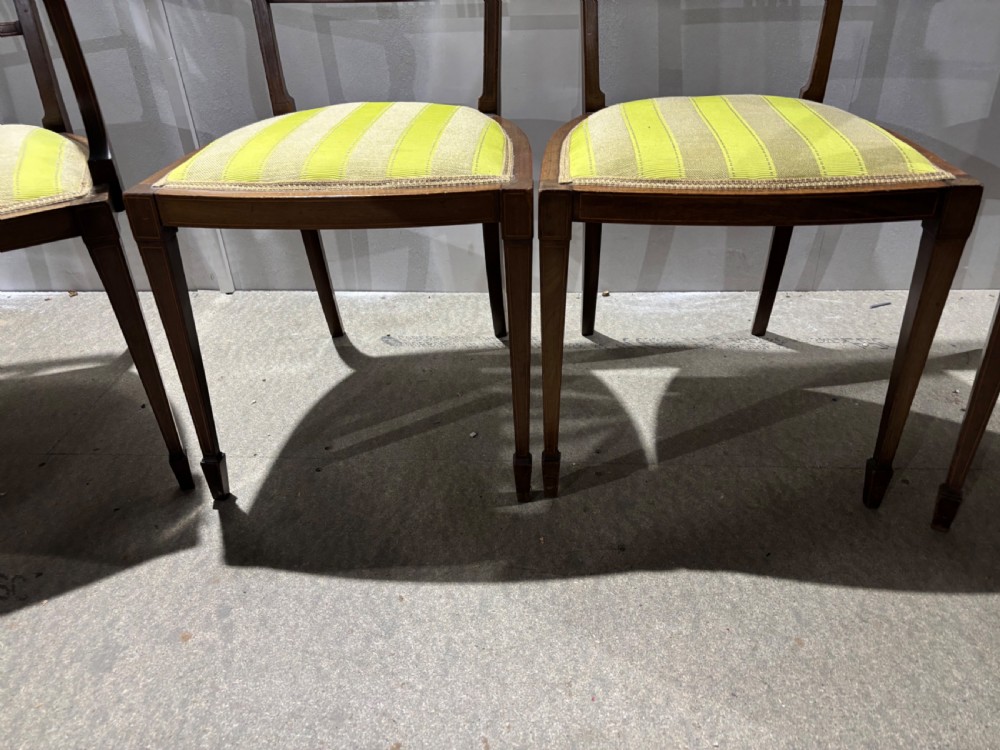 A set of four Edwardian mahogany salon chairs featuring fan-shaped pierced back splats, subtle string inlay, slender tapered legs, and yellow striped fabric seat cushions. View V