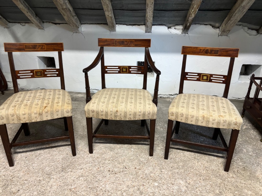 A set of three Georgian mahogany chairs featuring satinwood and brass inlay on the backrests with patterned fabric upholstered seats.