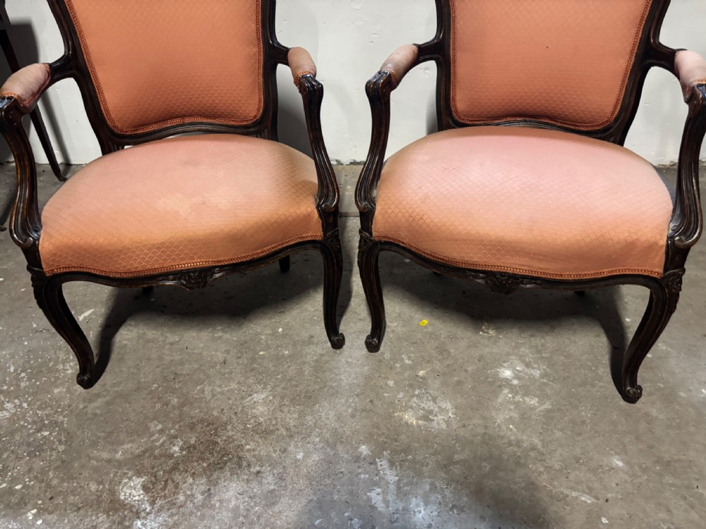 A pair of 19th-century French oak fauteuil armchairs featuring dark carved wood frames, padded armrests, cabriole legs, and peach fabric upholstery. View IV