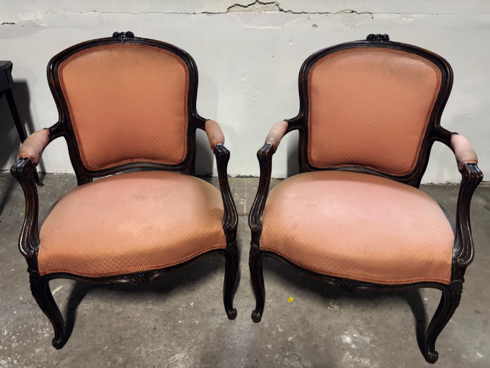 A pair of 19th-century French oak fauteuil armchairs featuring dark carved wood frames, padded armrests, cabriole legs, and peach fabric upholstery. View V