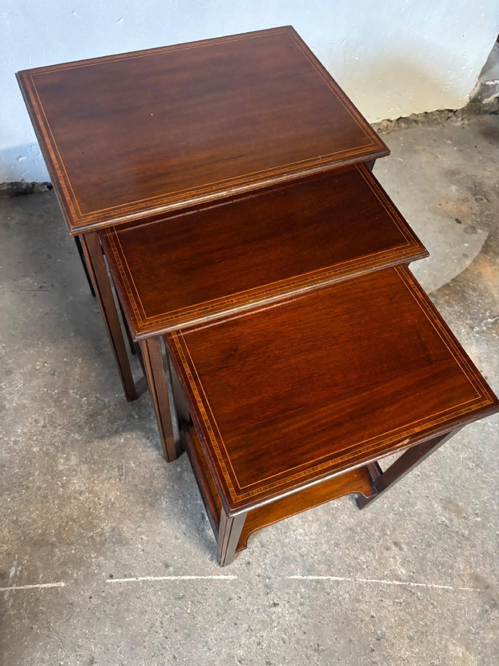 A set of three graduated Edwardian mahogany occasional tables featuring fine linear wood inlay around the rectangular top borders and slender square legs.