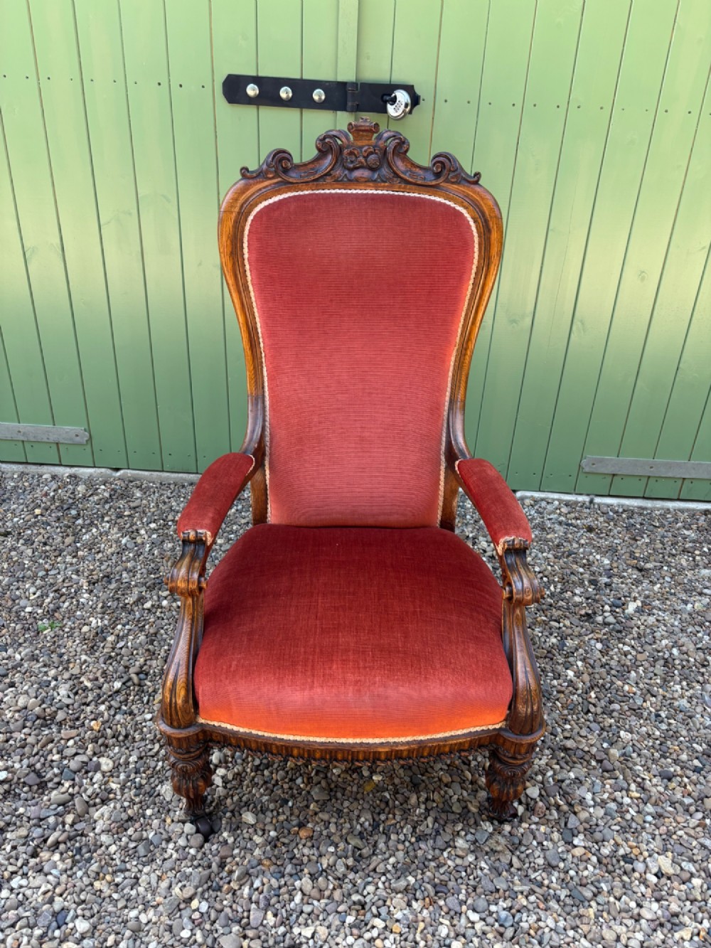 Victorian carved oak armchair featuring a high back upholstered in terracotta velvet with open arms and carved legs.