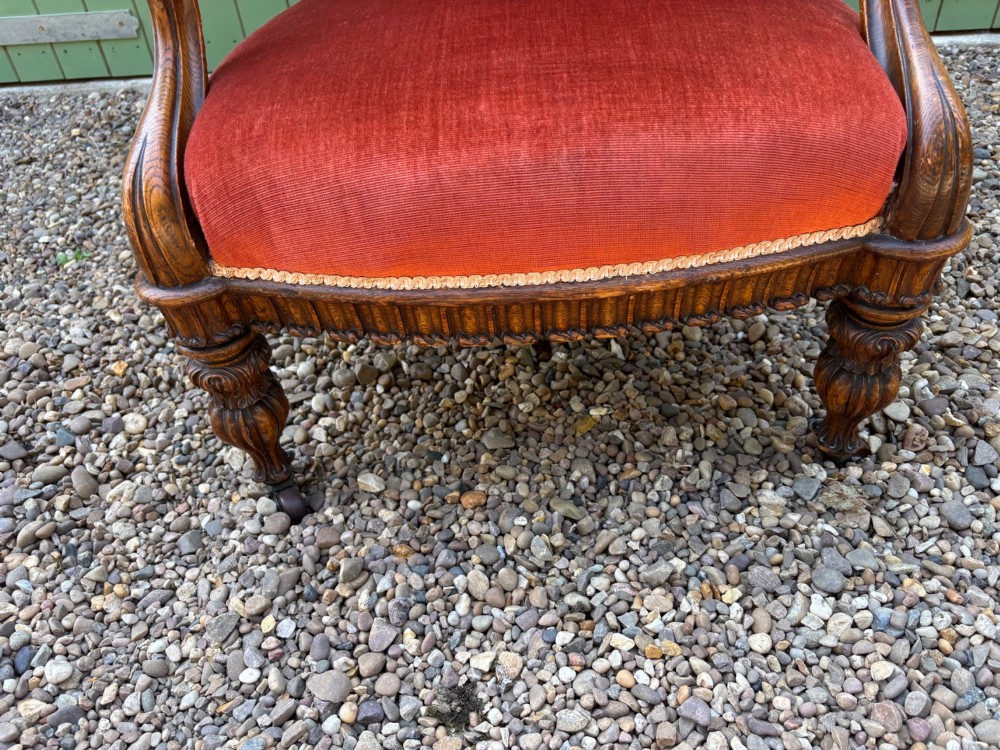 Victorian carved oak armchair featuring a high back upholstered in terracotta velvet with open arms and carved legs. View IV