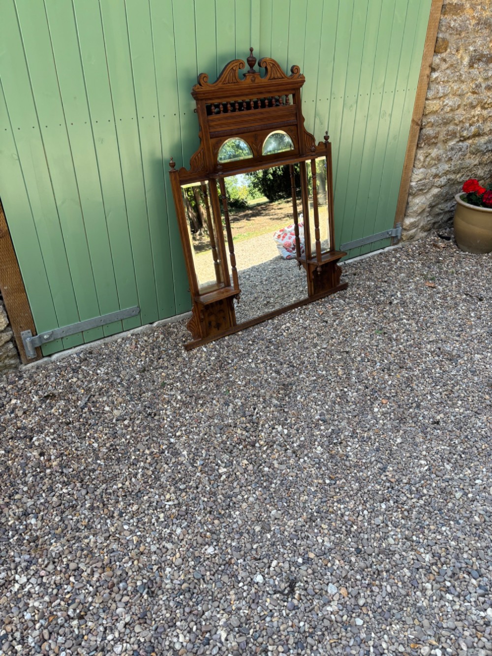 An Edwardian carved walnut overmantel mirror featuring multiple glass plates, integrated display shelves, turned columns, and a decorative crest with a central finial. View III
