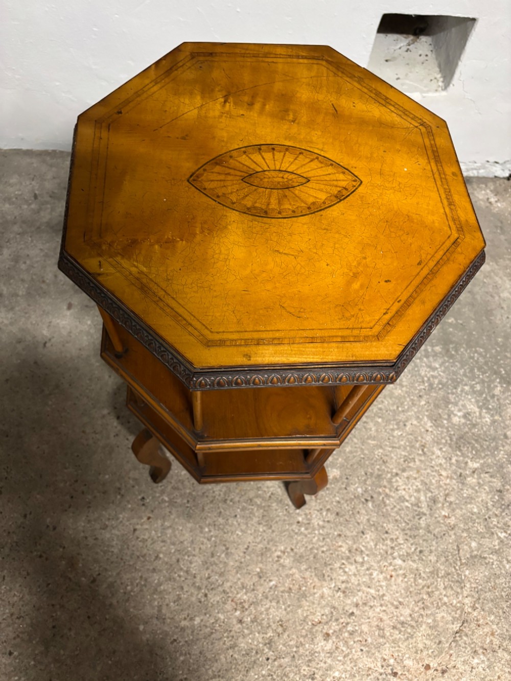 An Edwardian octagonal satinwood revolving bookcase featuring central marquetry inlay, spindle supports, two open tiers, and cabriole legs. View II