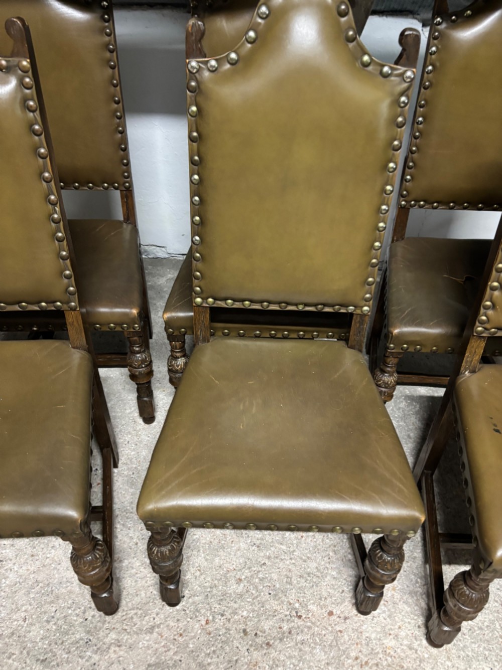 A set of eight oak dining chairs featuring arched olive leather backs and seats trimmed with brass studding. View II