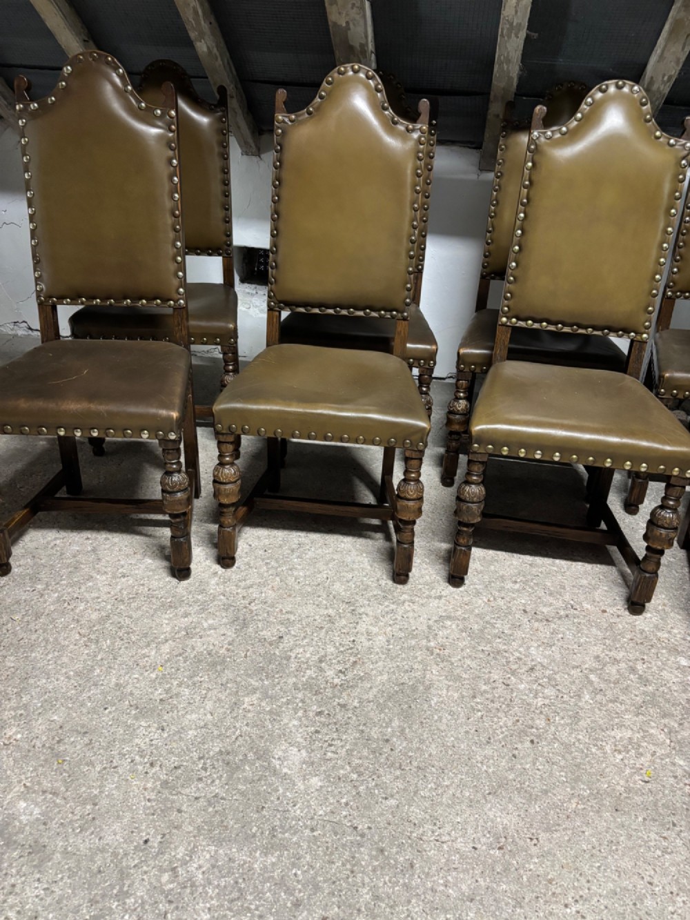 A set of eight oak dining chairs featuring arched olive leather backs and seats trimmed with brass studding. View VII