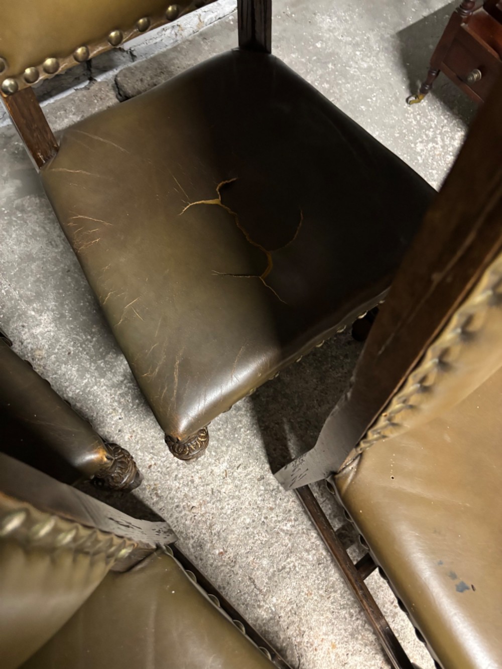 A set of eight oak dining chairs featuring arched olive leather backs and seats trimmed with brass studding. View VIII