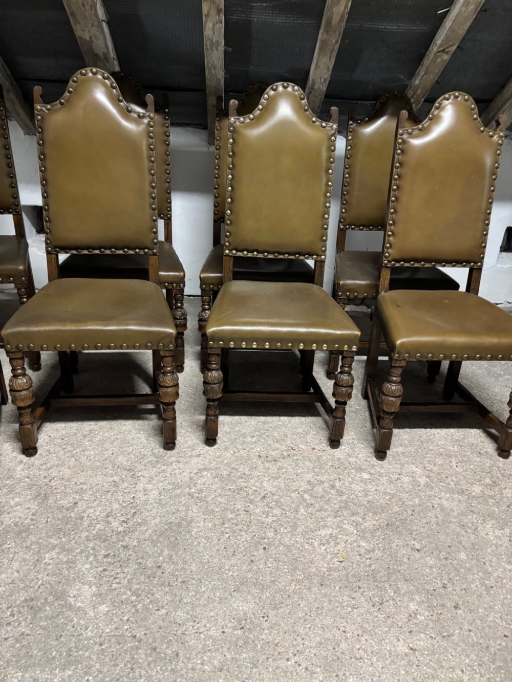 A set of eight oak dining chairs featuring arched olive leather backs and seats trimmed with brass studding. View IX