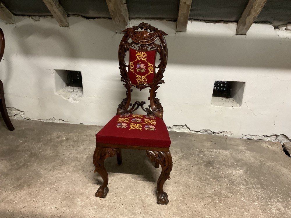 A 19th-century carved mahogany hall chair featuring an openwork backrest, cabriole legs, and crimson tapestry upholstery with floral needlepoint.