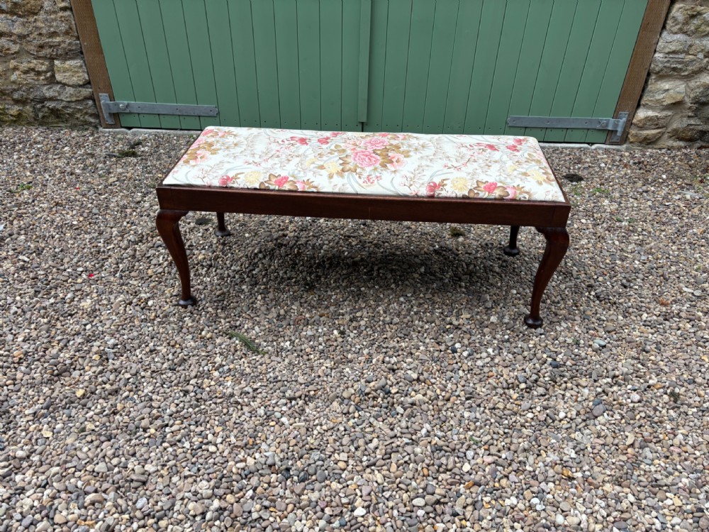 A George III mahogany duet stool featuring a floral upholstered rectangular top and cabriole legs ending in pad feet.