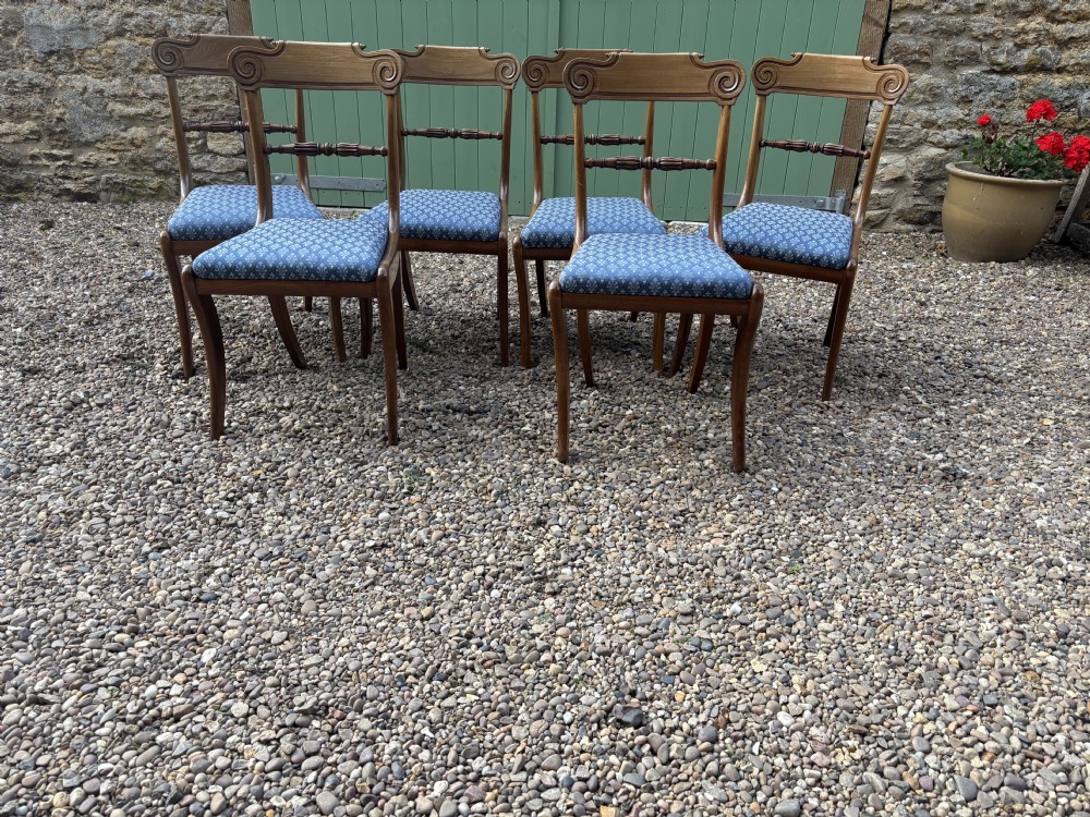 A set of six Regency mahogany dining chairs featuring scrolled top rails, turned horizontal crossbars, and blue patterned upholstered seats.