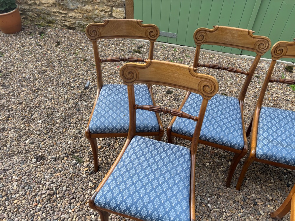 A set of six Regency mahogany dining chairs featuring scrolled top rails, turned horizontal crossbars, and blue patterned upholstered seats. View V