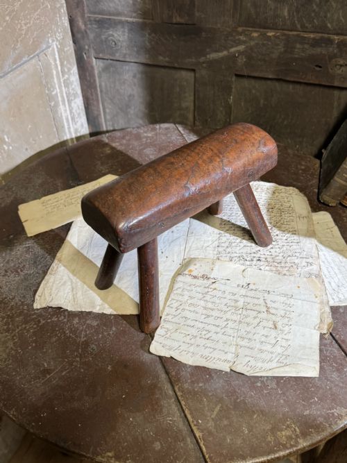 fig 1. A small antique dark timber vernacular stool with a sculpted rounded top and four splayed legs.