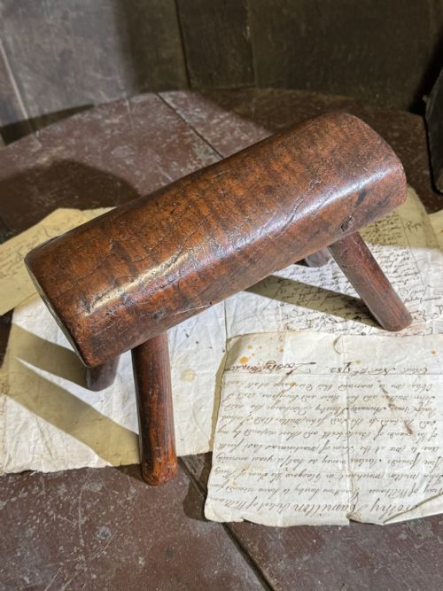 fig 2. A small antique dark timber vernacular stool with a sculpted rounded top and four splayed legs.