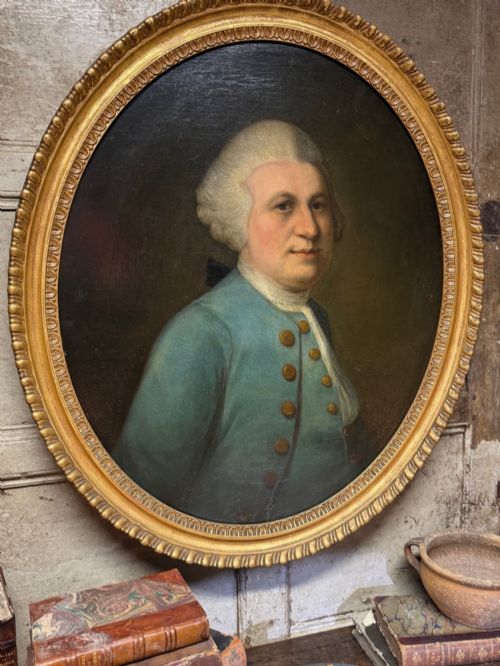 fig 1. An 18th-century oval oil portrait depicting a gentleman in a blue coat and wig, set inside a carved giltwood frame.