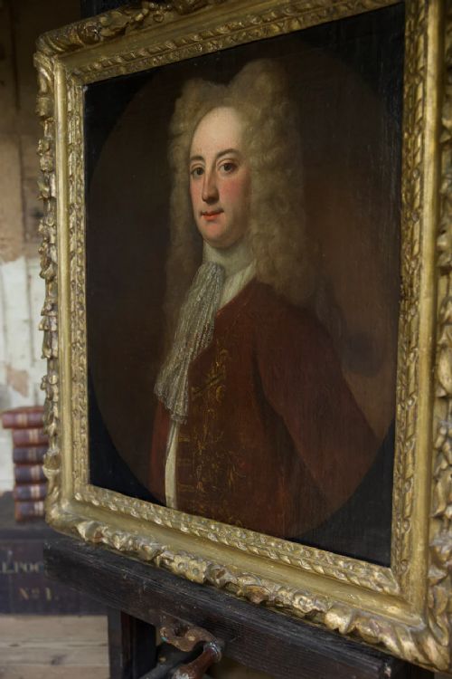 fig 4. An early 18th-century oil portrait depicting a gentleman in a crimson coat and powdered wig, set within a heavily carved gilded frame.