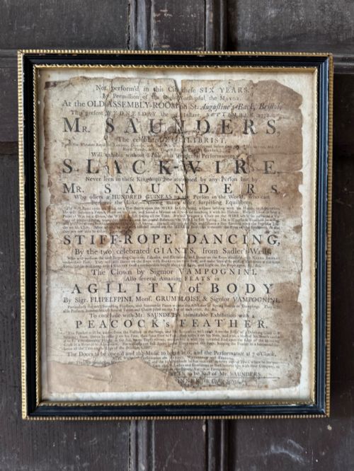 fig 1. An 18th-century paper handbill with black letterpress typography advertising performance acts, displayed in a black frame with a gilt inner border.