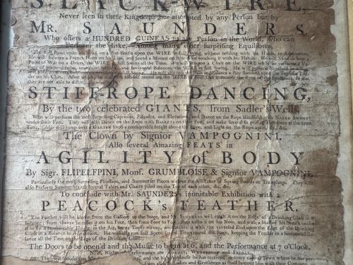 fig 3. An 18th-century paper handbill with black letterpress typography advertising performance acts, displayed in a black frame with a gilt inner border.