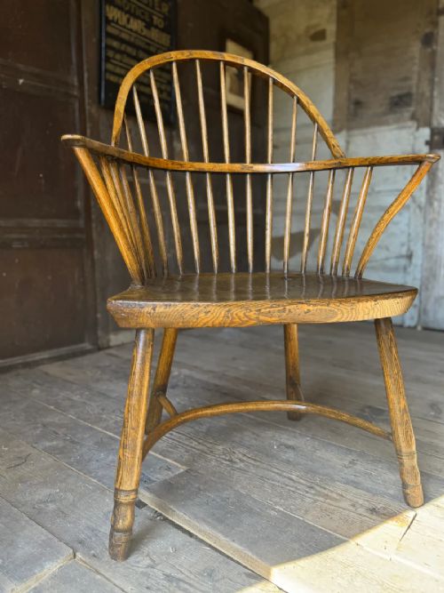 fig 4. A George III West Country Windsor armchair made of elm and ash wood, featuring a spindled backrest, shaped timber seat, turned legs, and a cow-horn stretcher.