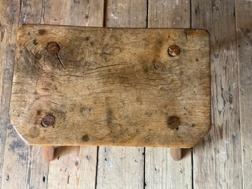 fig 3. An early 19th-century rustic wooden stool featuring a rectangular sycamore seat top with visible wedged through-tenons and four splayed ash legs.