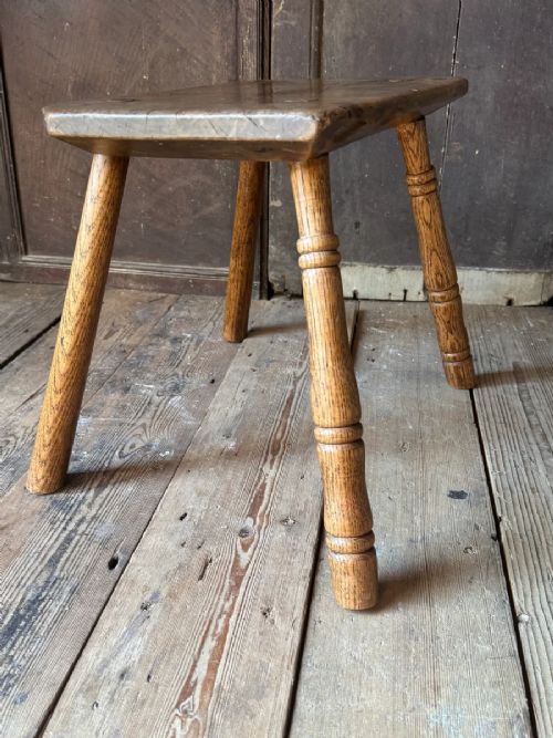 fig 4. An early 19th-century rustic wooden stool featuring a rectangular sycamore seat top with visible wedged through-tenons and four splayed ash legs.