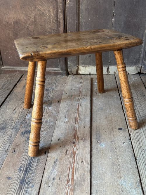 An early 19th-century rustic wooden stool featuring a rectangular sycamore seat top with visible wedged through-tenons and four splayed ash legs. View VI
