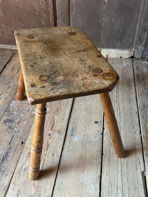An early 19th-century rustic wooden stool featuring a rectangular sycamore seat top with visible wedged through-tenons and four splayed ash legs. View X