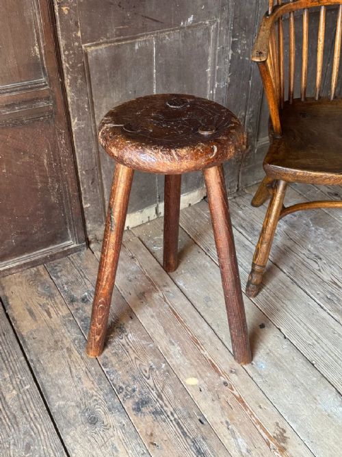 A 19th-century rustic three-legged wooden stool featuring a thick dished circular elm seat and splayed turned legs. View II