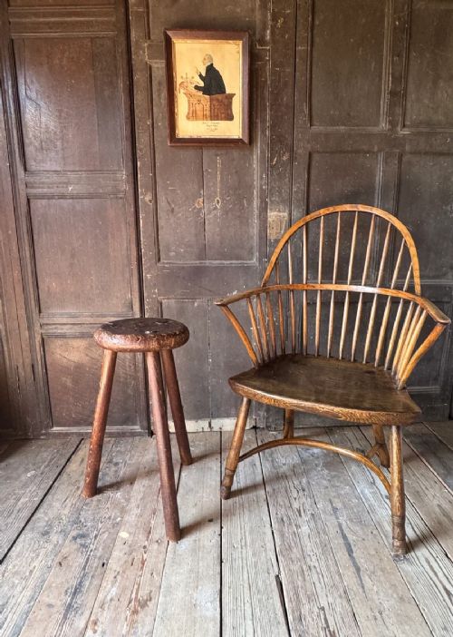 A 19th-century rustic three-legged wooden stool featuring a thick dished circular elm seat and splayed turned legs. View VIII