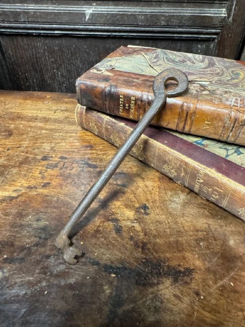 An 18th-century hand-forged wrought iron skeleton key featuring a looped bow handle, elongated cylindrical stem, and angled notched bit. View II