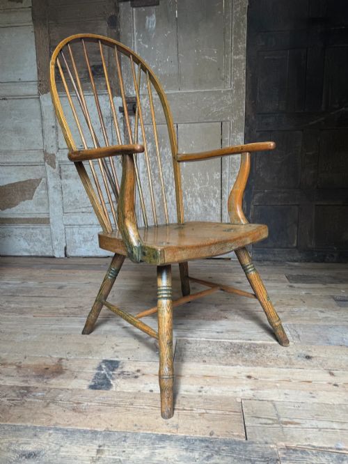 fig 1. A George III high hoop-back Windsor armchair crafted from elm and ash with turned legs and a carved timber seat.
