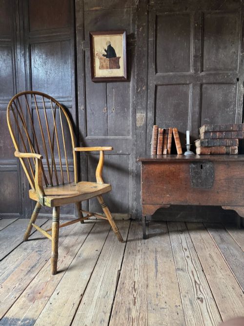 fig 4. A George III high hoop-back Windsor armchair crafted from elm and ash with turned legs and a carved timber seat.