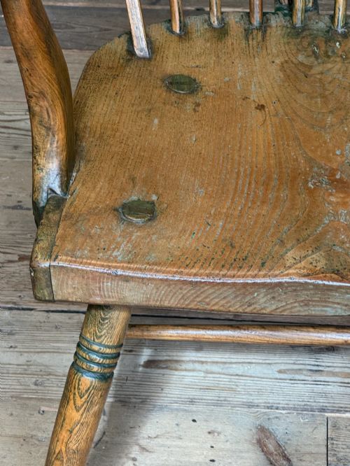 fig 5. A George III high hoop-back Windsor armchair crafted from elm and ash with turned legs and a carved timber seat.
