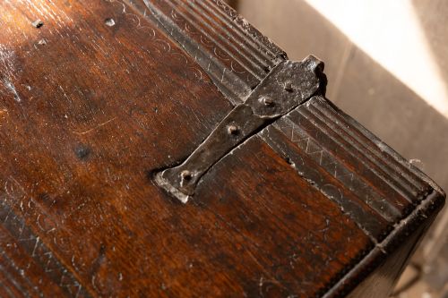 fig 5. An Elizabethan carved oak boarded chest featuring relief carvings of winged mythical beasts, an iron lockplate, and slab end legs.