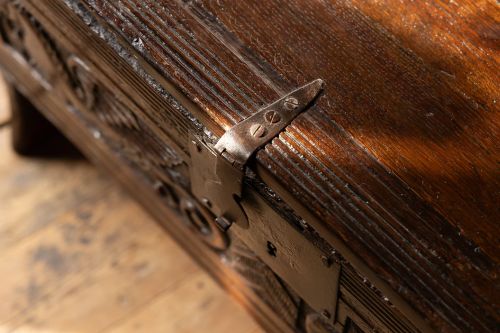 fig 6. An Elizabethan carved oak boarded chest featuring relief carvings of winged mythical beasts, an iron lockplate, and slab end legs.