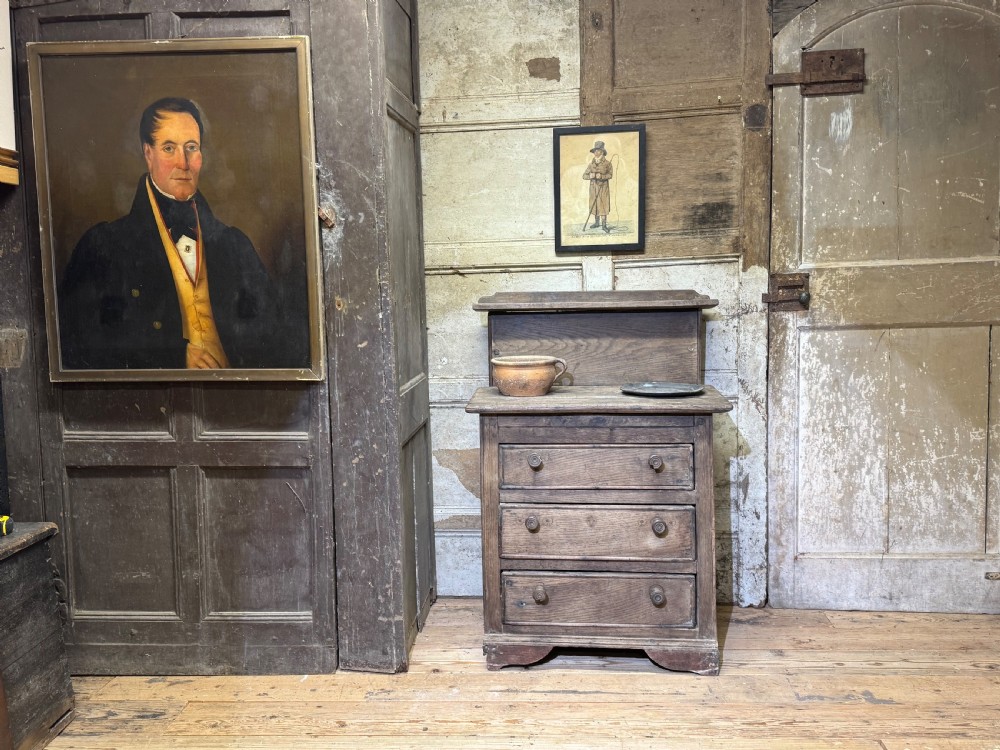 A small early 19th-century primitive oak chest featuring three drawers with turned wooden knobs and a raised wooden back shelf. View III