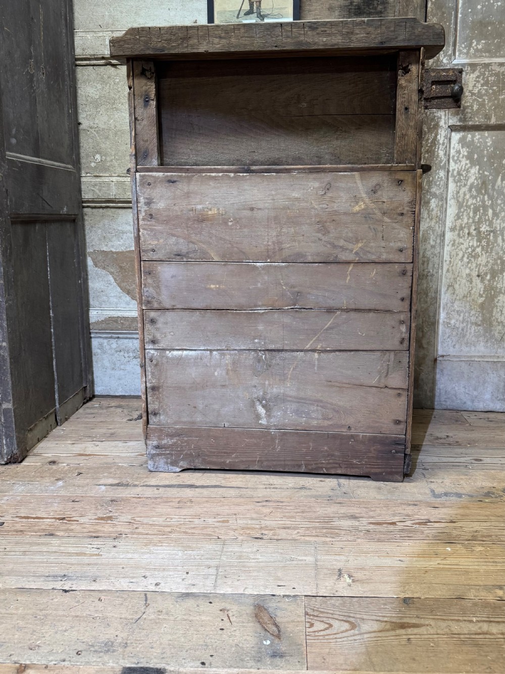 A small early 19th-century primitive oak chest featuring three drawers with turned wooden knobs and a raised wooden back shelf. View X