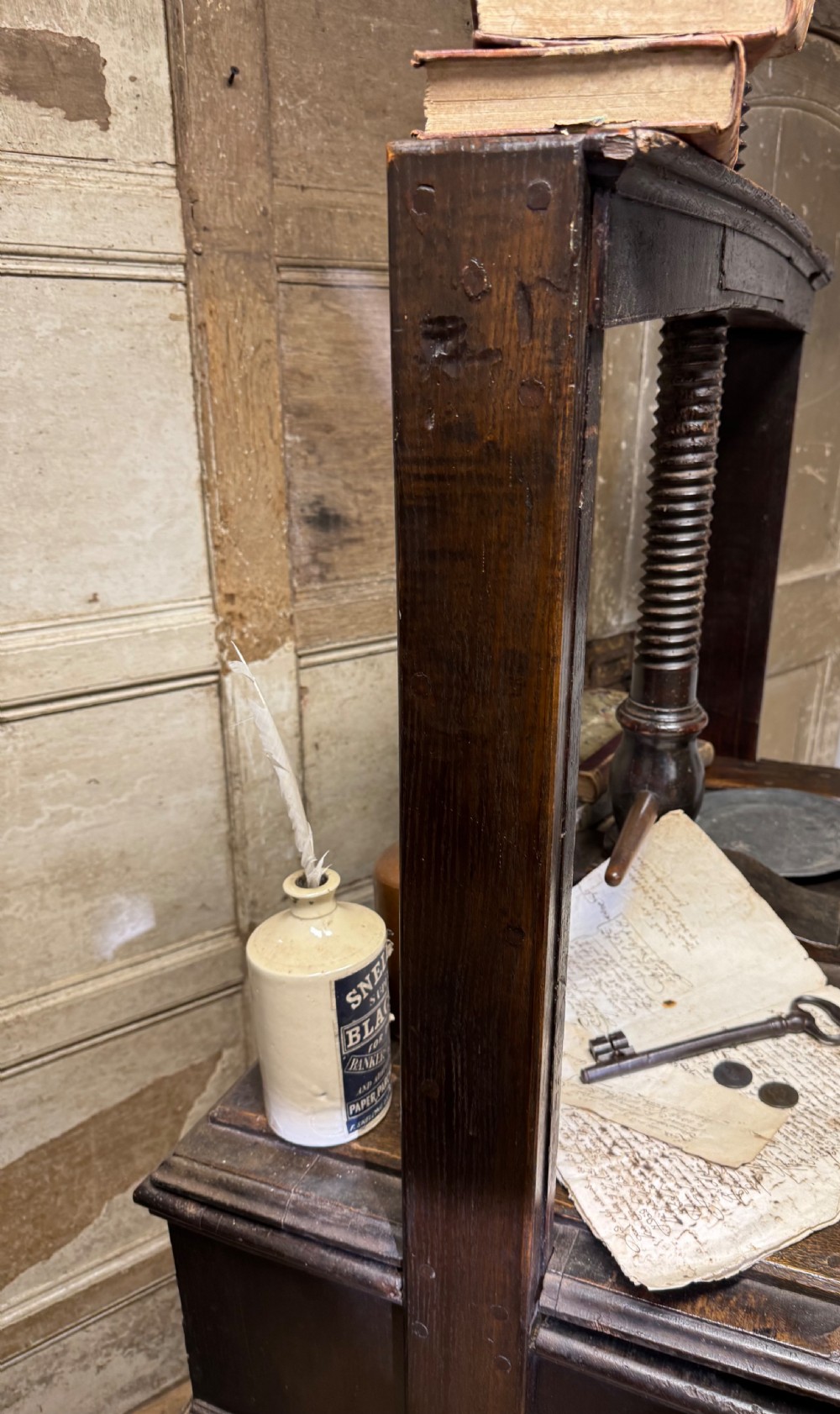 A George III provincial dark wood linen press with a turned screw mechanism mounted above a single drawer base on square legs. View VII