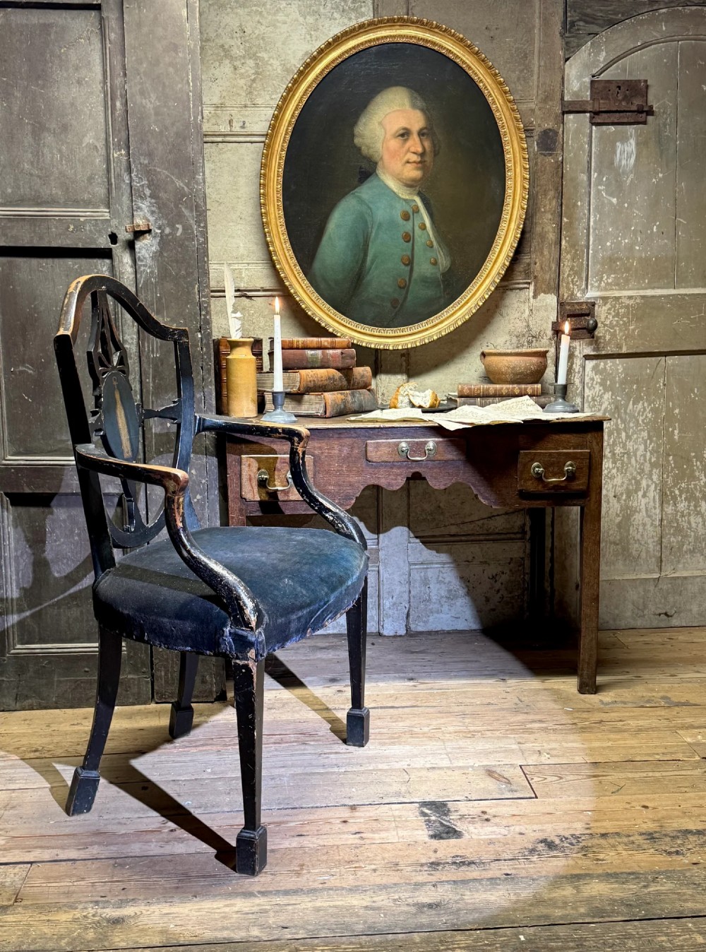 An 18th-century oval oil portrait depicting a gentleman in a blue coat and wig, set inside a carved giltwood frame. View III