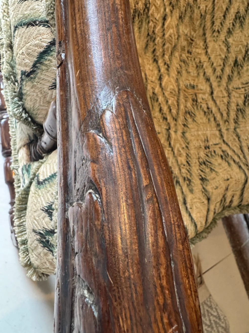 An early eighteenth-century French oak wingback armchair featuring patterned fabric upholstery, carved scroll armrests, and turned legs with stretchers. View IV