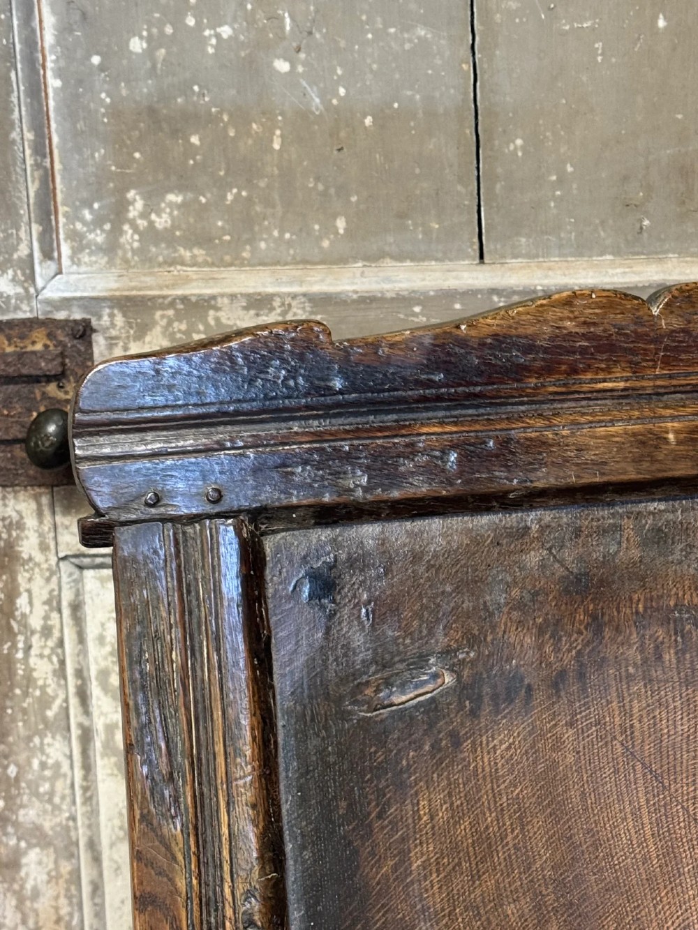 A 17th-century solid dark oak wainscot armchair featuring a panelled backrest, turned front legs, and wooden armrests. View VI