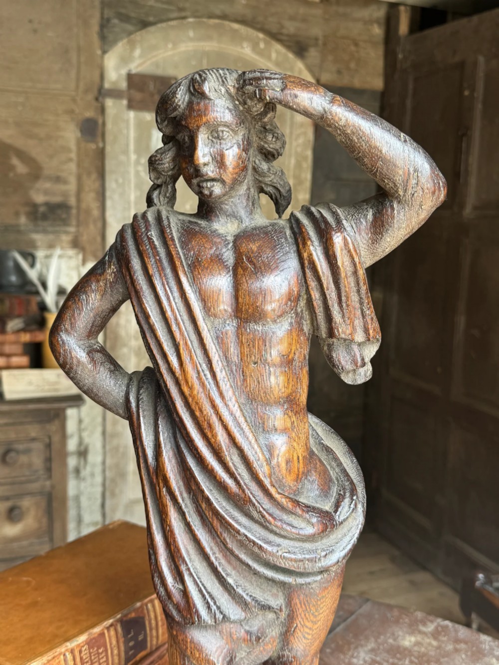 An 18th-century carved oak standing male figure with drapery across his shoulder set on a rounded base. View II