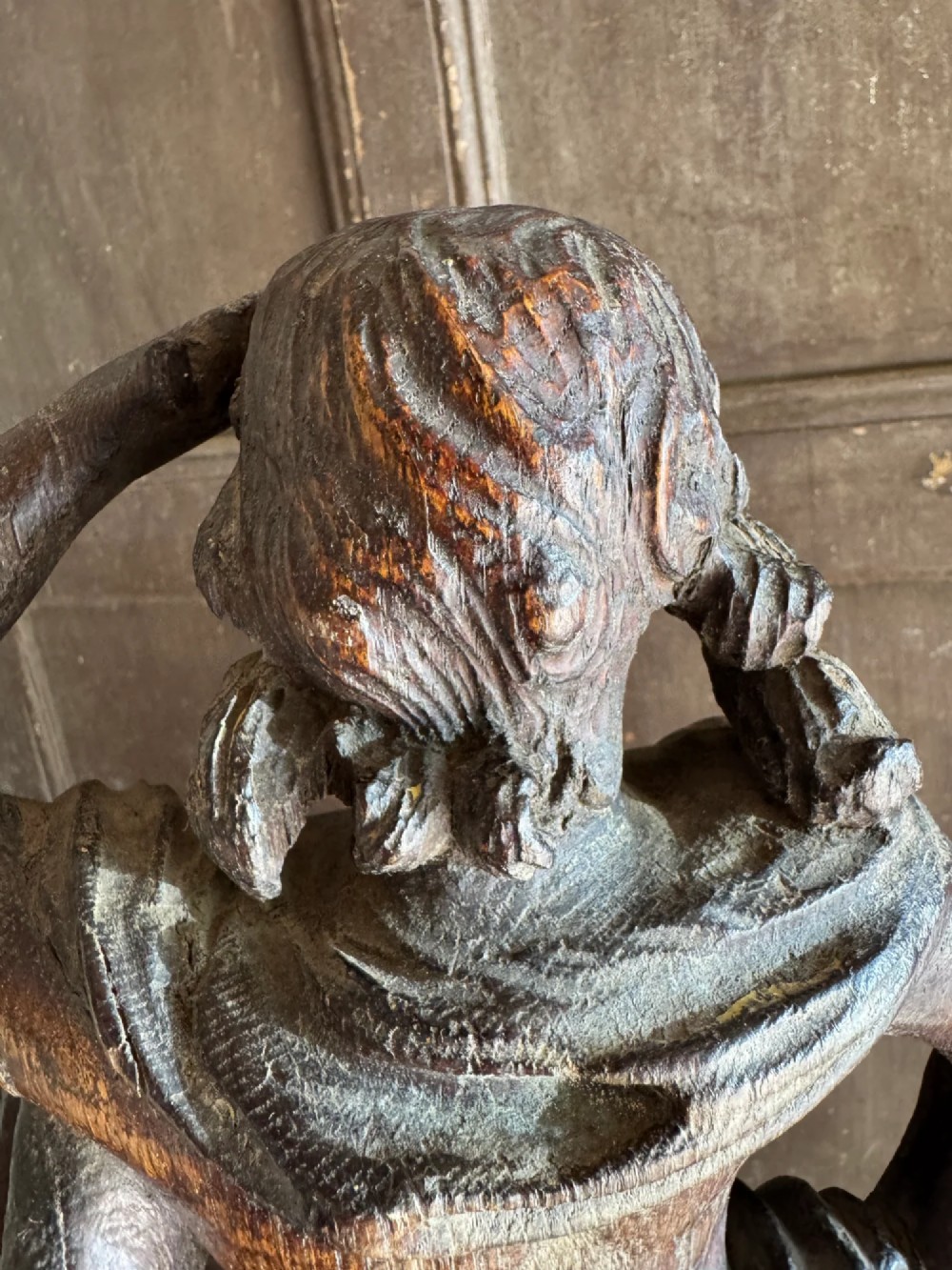 An 18th-century carved oak standing male figure with drapery across his shoulder set on a rounded base. View V