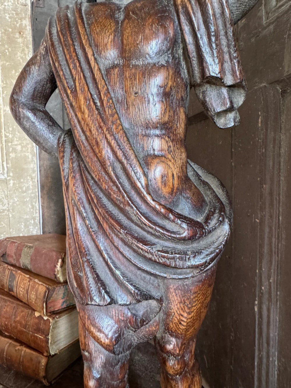 An 18th-century carved oak standing male figure with drapery across his shoulder set on a rounded base. View X