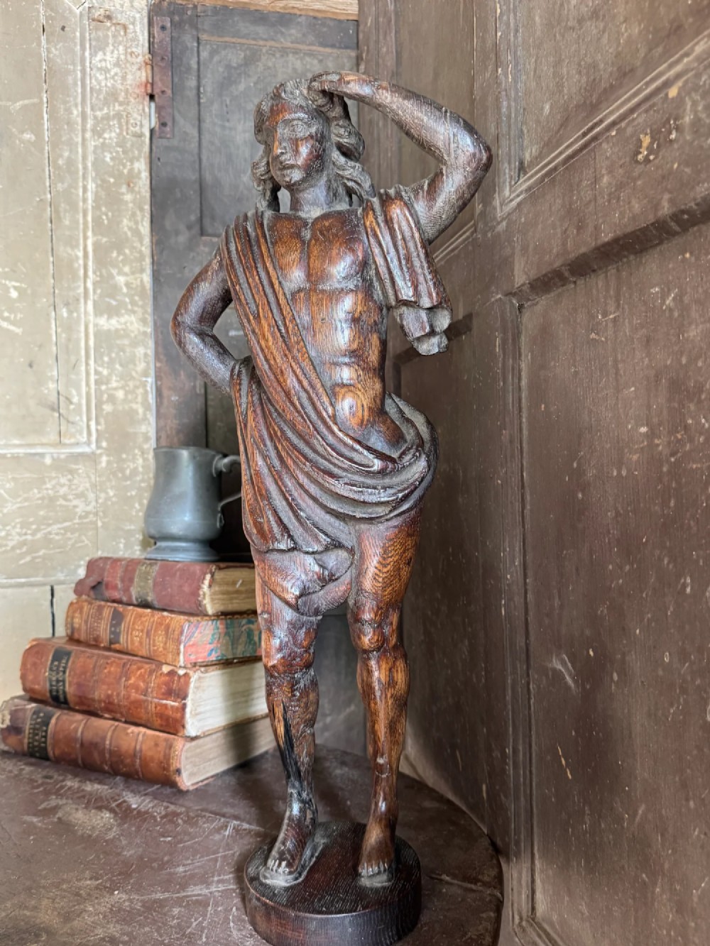 An 18th-century carved oak standing male figure with drapery across his shoulder set on a rounded base. View XI