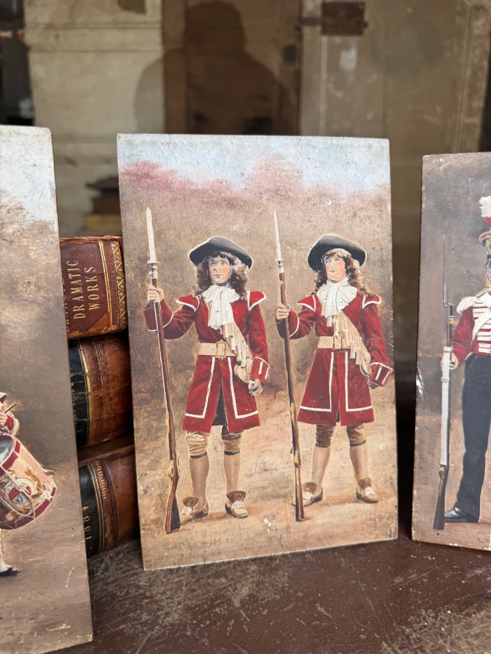 A set of four early twentieth-century wooden panels featuring hand-painted depictions of military soldiers in red uniform coats. View II