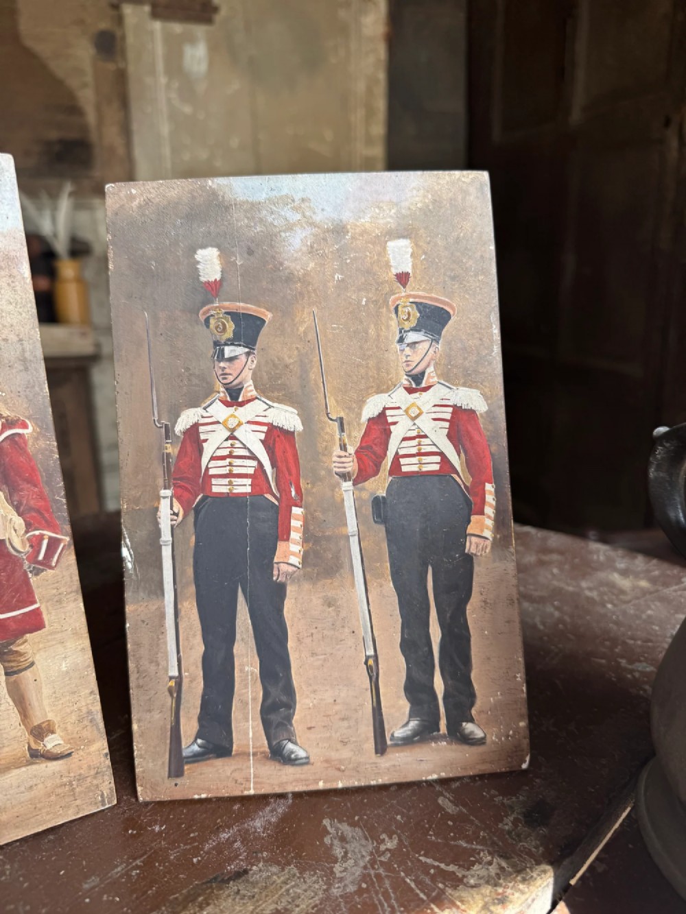 A set of four early twentieth-century wooden panels featuring hand-painted depictions of military soldiers in red uniform coats. View III